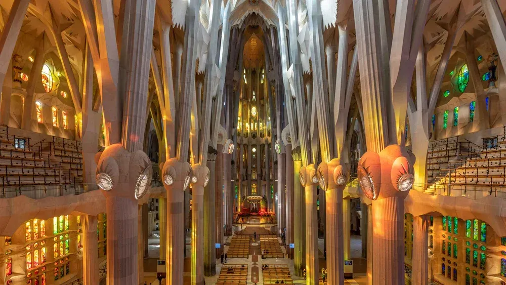 Visitor holding a phone audio guide under the branching stone columns on a self-guided la sagrada familia tour
